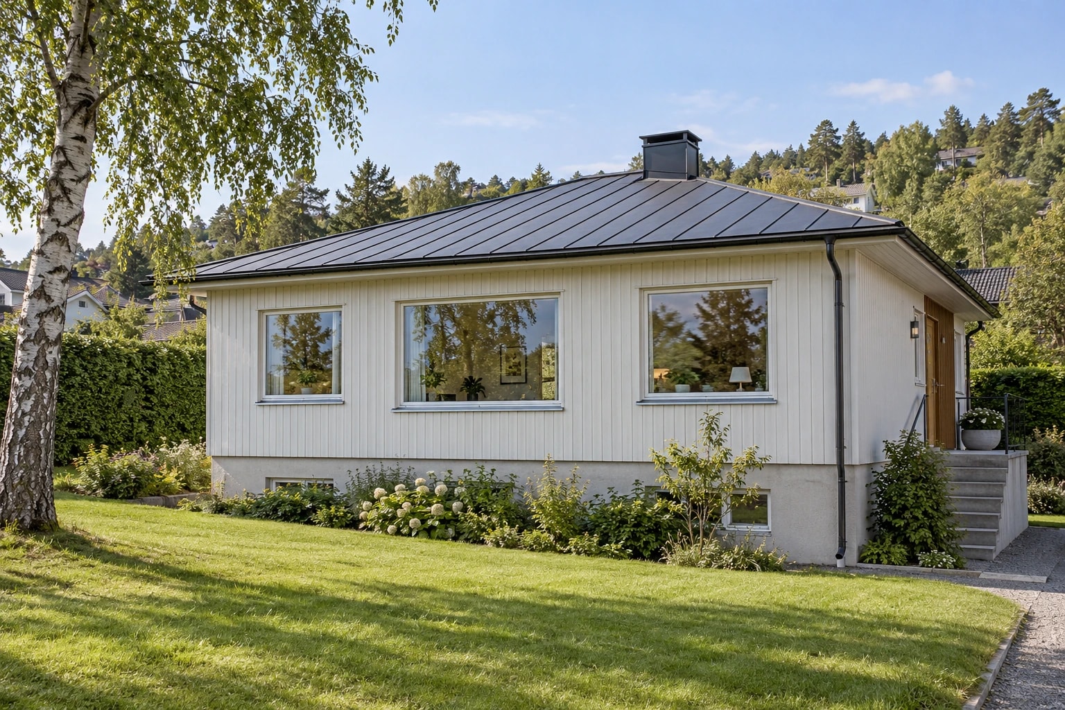 Lys trebolig med metalltak, store vinduer og metallbeslag under vinduene.